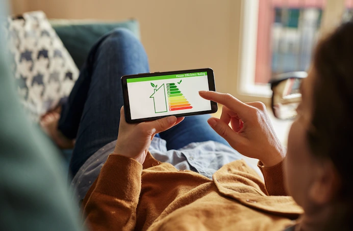 Man kijkt naar de energiezuinigheid van zijn woning terwijl hij in de zetel ligt